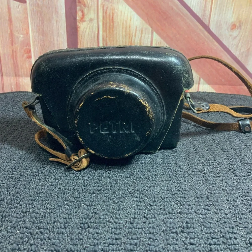 Vintage Petri camera with leather strap and cover.