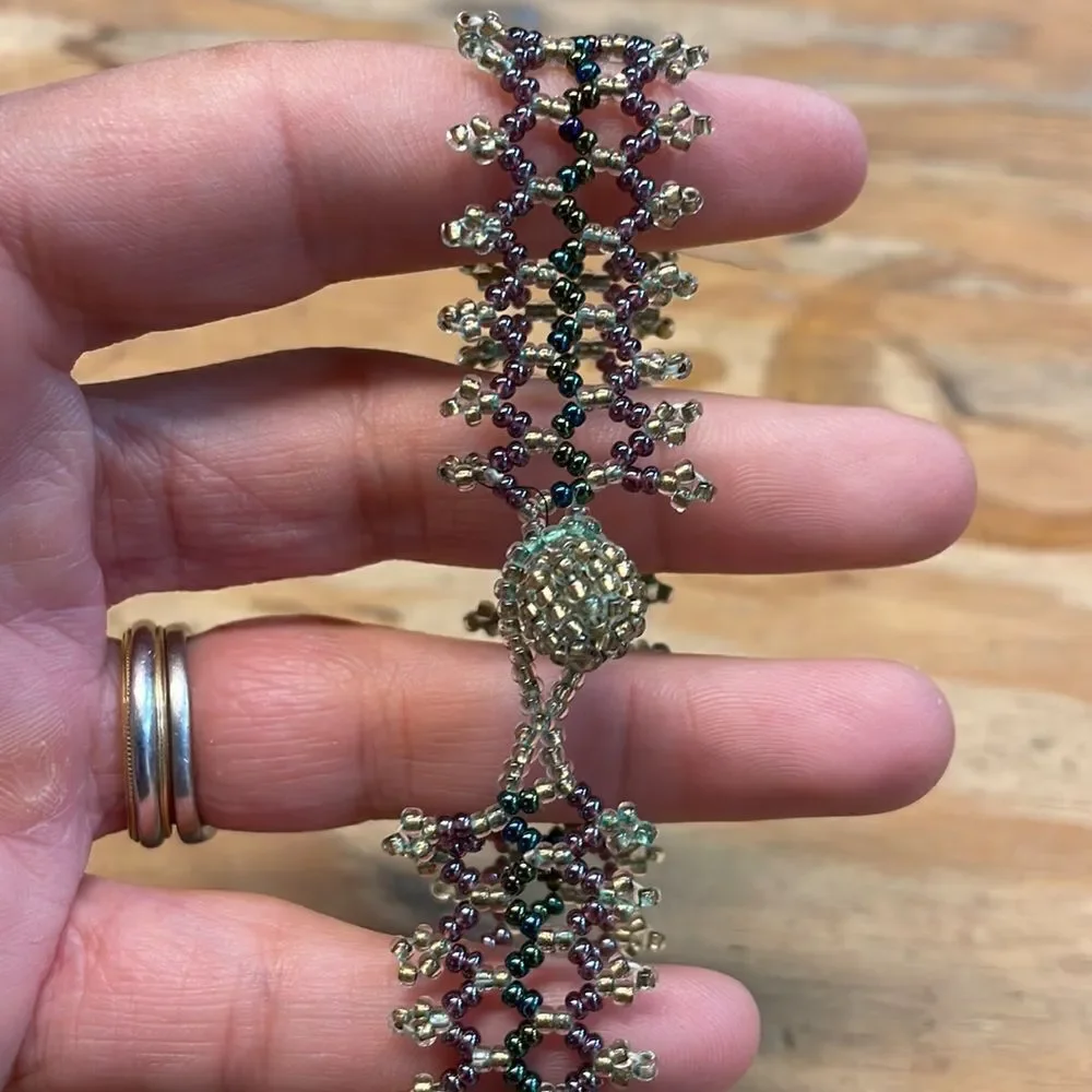 Woman’s beaded bracelet. Colors are gold,green and purple