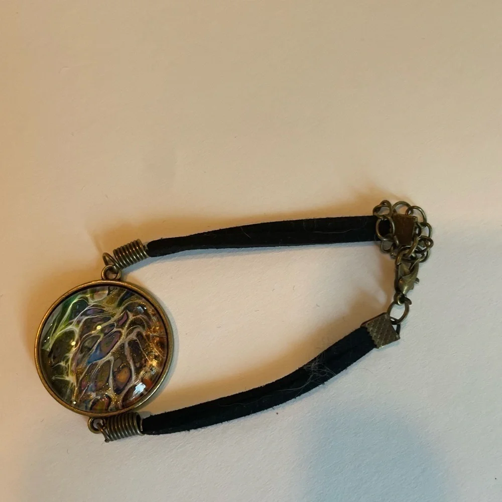 Hand painted acrylic design on glass bracelet.  Attached to metal.  Adjustable