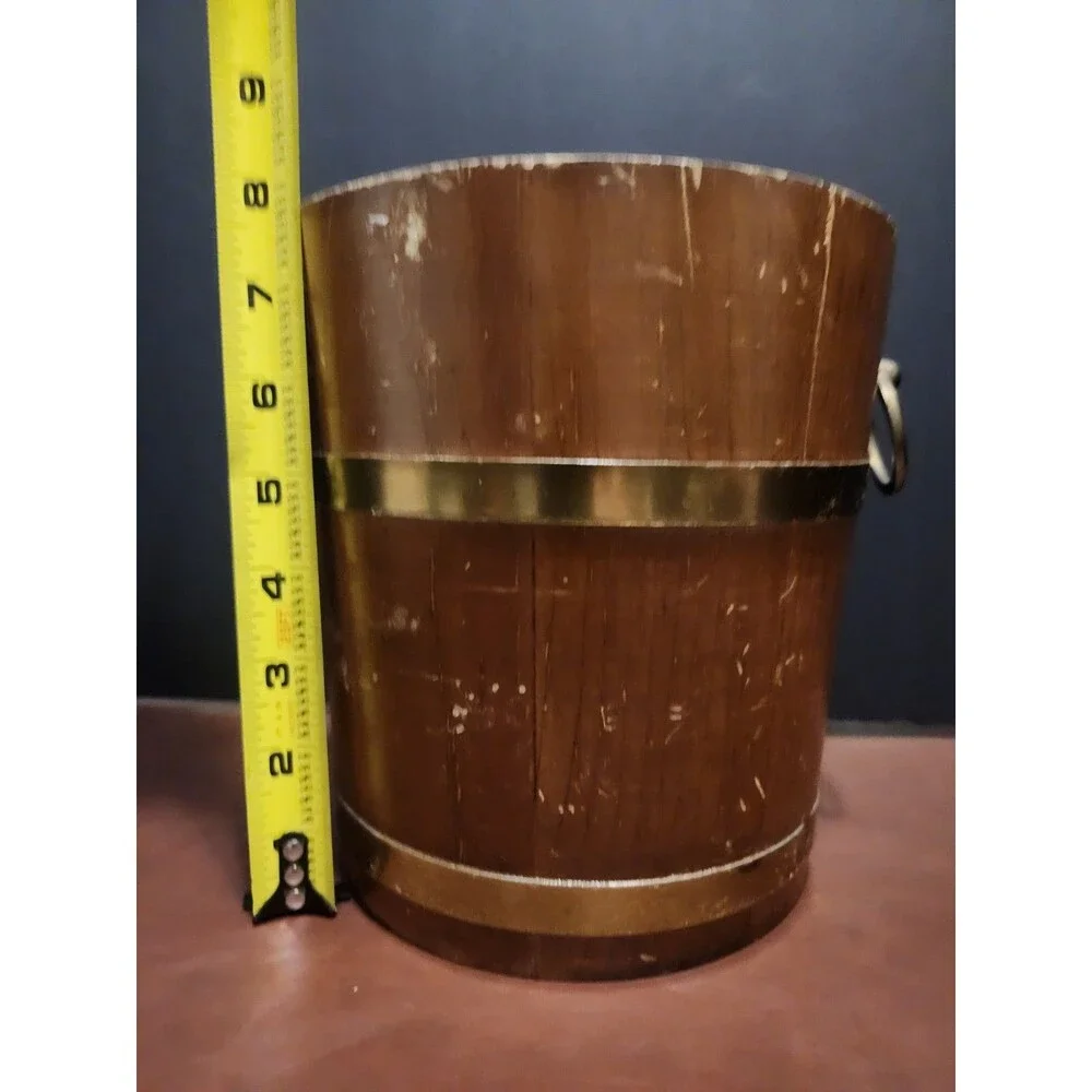 This is a vintage wood and brass barrel-style ice bucket typically measuring...