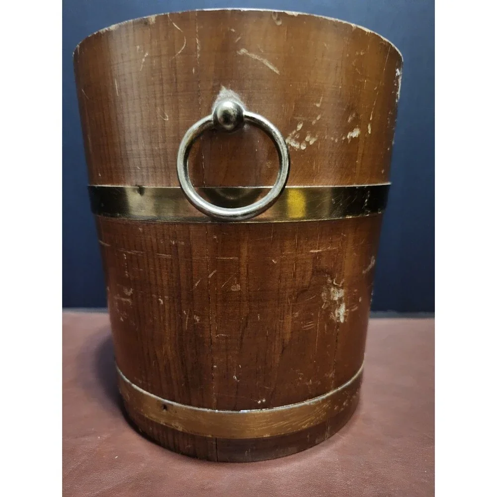 This is a vintage wood and brass barrel-style ice bucket typically measuring...